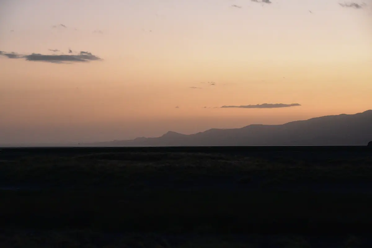 Ciel orange à l’aube au-dessus de la plaine sombre du lac Natron