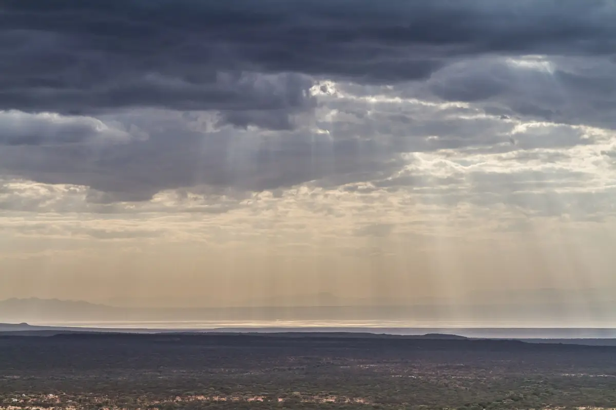Lichtstrahlen durch Gewitterwolken über der Ebene am Natronsee